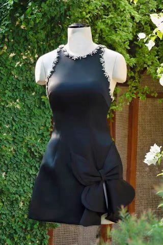 Black dress on a mannequin against a green leafy background