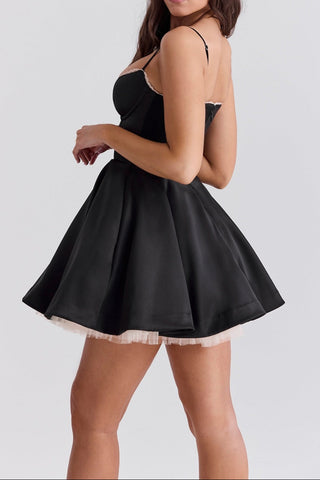 Woman wearing a black dress with thin straps on a light gray background