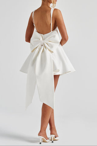 White dress with a large bow detail on the back, worn by a person on a plain background